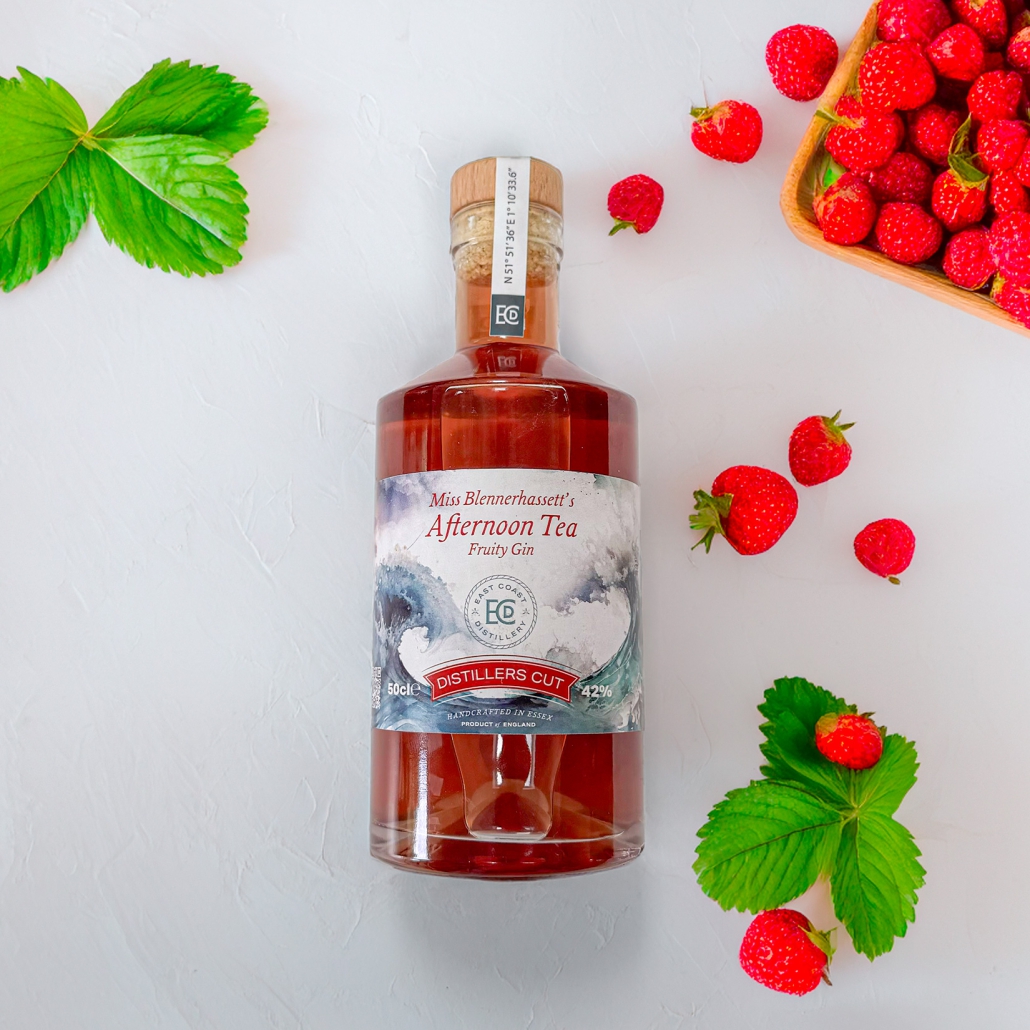 bottle of red fruit gin on a plain background surrounded by strawberries